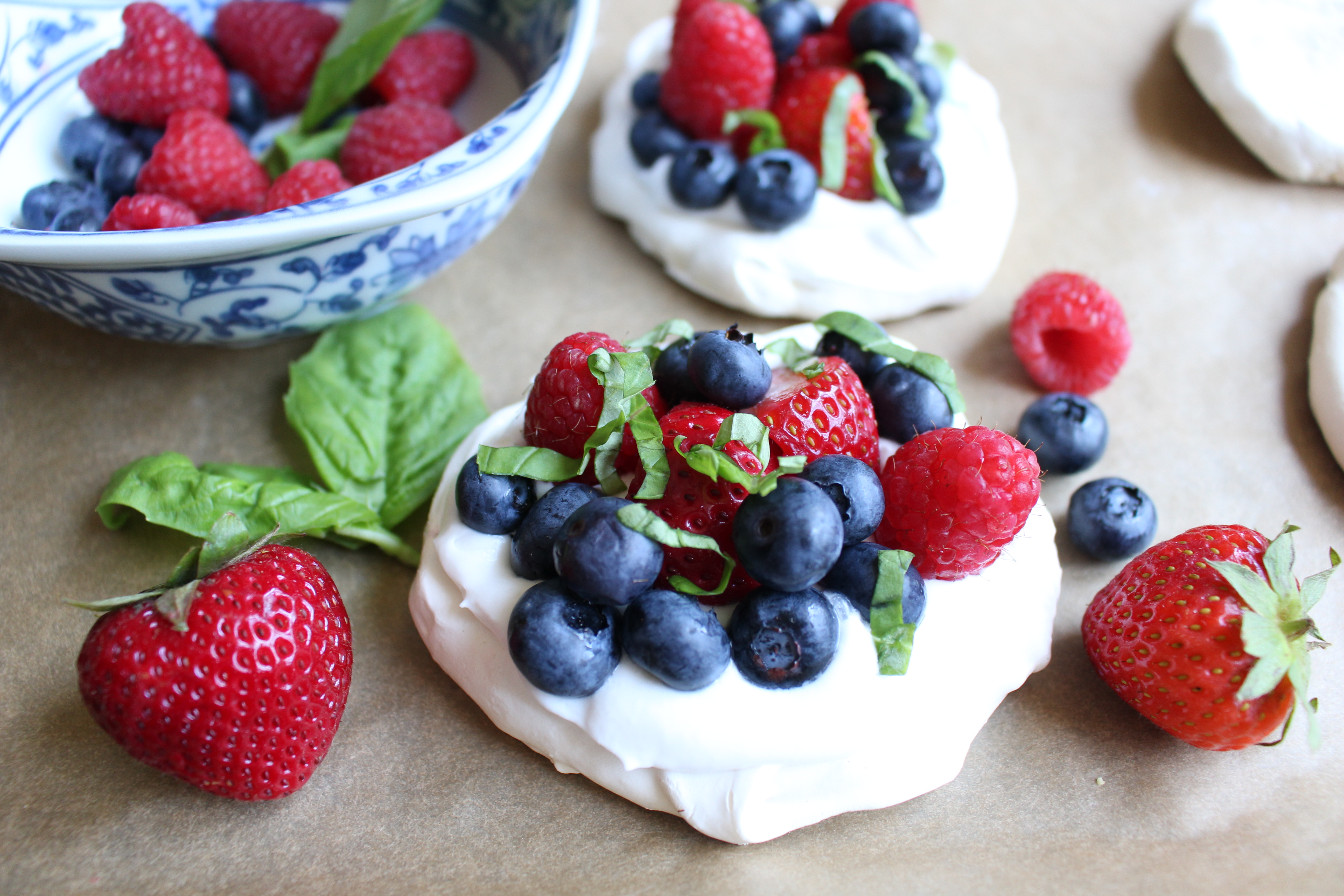 These meringues, topped with coconut whipped cream, fresh berries, and chopped basil, are the perfect summer dessert - light, airy, and fresh!
