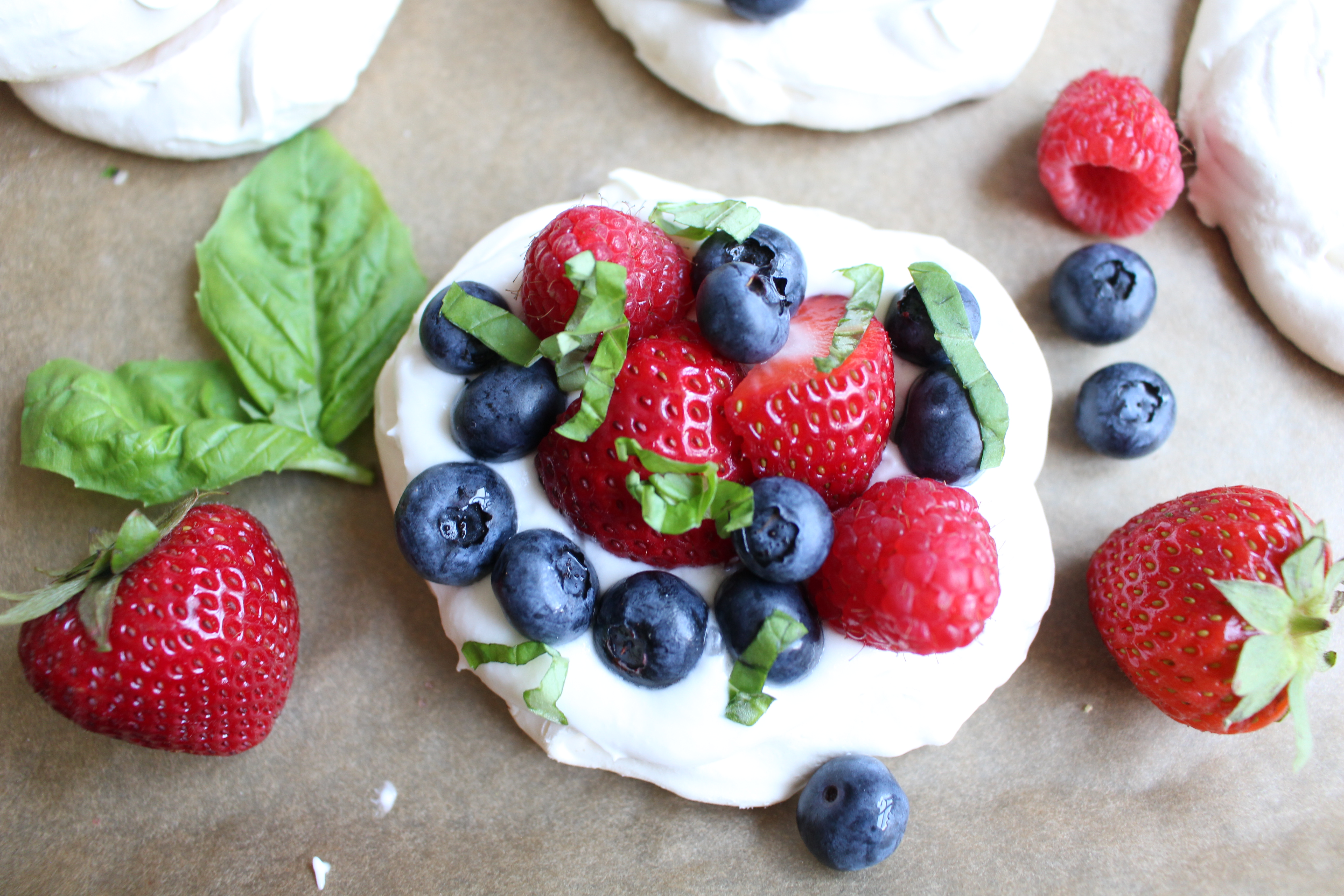 These meringues, topped with coconut whipped cream, fresh berries, and chopped basil, are the perfect summer dessert - light, airy, and fresh!